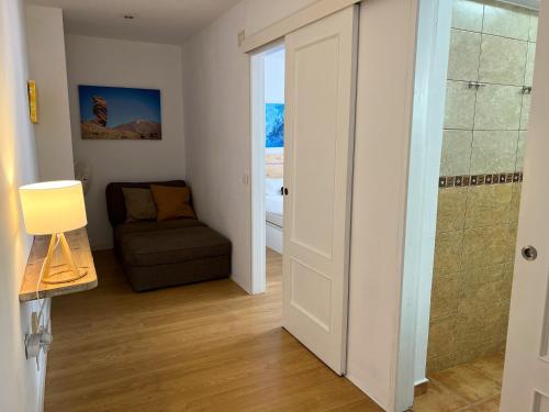 une salle de bain avec douche et un canapé dans une chambre dans l'établissement Hibiscus Apartment, à Bajamar