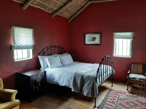 um quarto com uma cama numa parede vermelha em Zeekoegat Historical Homestead em Riversdale