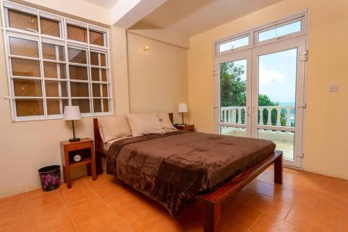 um quarto com uma cama e uma grande janela em Oceanfront 3-bedroom villa with spectacular view! em Calibishie