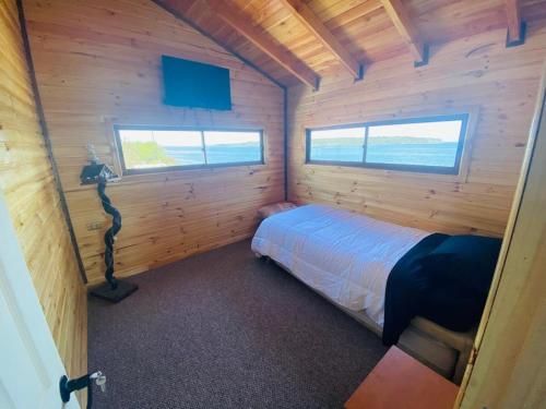 a bedroom with a bed in a wooden cabin at cabañas M&V in Quellón