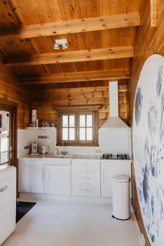 a kitchen with white cabinets and a wooden ceiling at HOLLAND Holiday Home in Ermelo