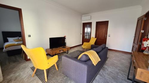 a living room with a couch and chairs and a tv at Santa Luzia Apt I in Ribeira Grande