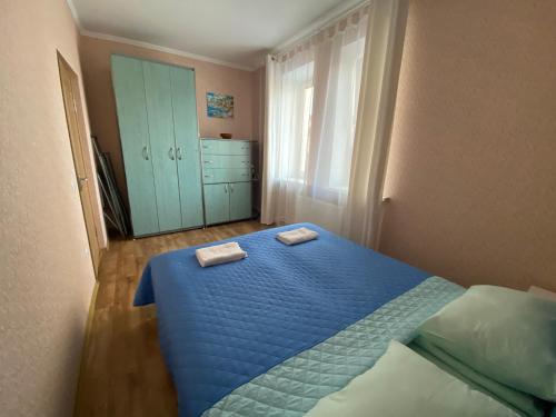 a bedroom with a blue bed with two towels on it at Апартаменты на проспекте in Vinnytsya