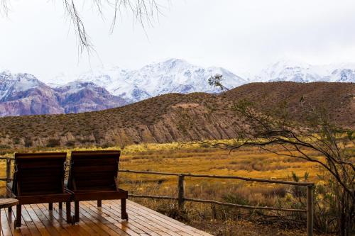 a bench sitting on a wooden deck looking at a mountain at Domos Uspallata in Uspallata