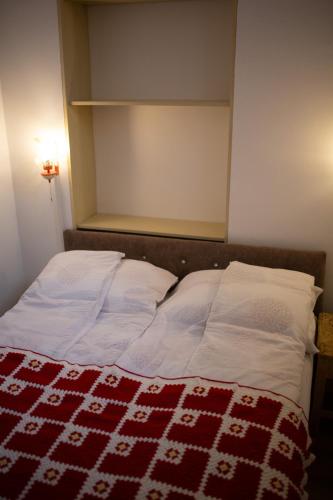 a bed with a red and white blanket on it at Apartments & Room - Korzo in Sombor