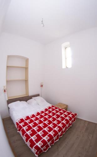 a bedroom with a bed with a red blanket on it at Apartments & Room - Korzo in Sombor