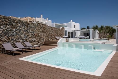 a swimming pool on a deck with chairs and a house at Villa in Mykonos in Mikonos