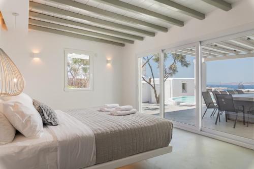 a white bedroom with a bed and a balcony at Villa in Mykonos in Mikonos