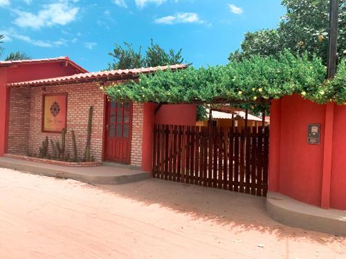 une maison rouge avec un portail et une clôture dans l'établissement Pousada Viva Barra, à Barra Grande