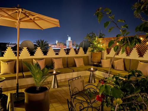 a rooftop patio with a couch and an umbrella at La Claire Fontaine in Marrakech