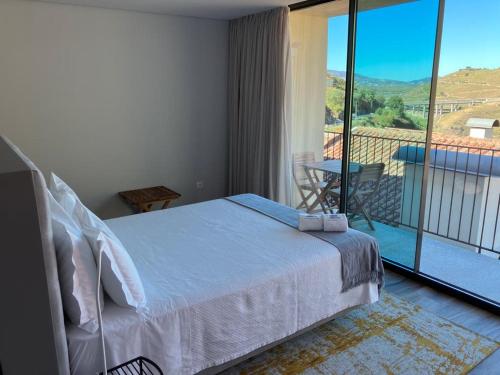 a bedroom with a bed and a balcony with a view at DouroXisto in Peso da Régua