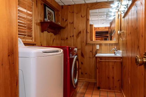 cocina con lavadora y fregadero en Pine Springs Retreat with Hot Tub Steam Room Lake Kushog, en Algonquin Highlands