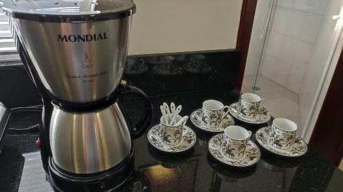 a coffee maker with cups and saucers on a counter at Lindos Studios Centro/Wifi/Garagem in Foz do Iguaçu