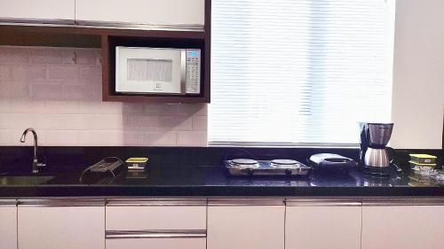 a kitchen with a black counter top and a microwave at Lindos Studios Centro/Wifi/Garagem in Foz do Iguaçu