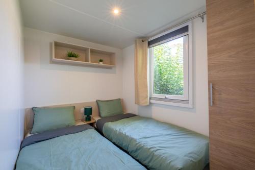 2 Betten in einem kleinen Zimmer mit Fenster in der Unterkunft Little John in Fréjus