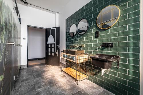 Łazienka z umywalką i ścianą z zielonej cegły w obiekcie VARSAVIA Hostel w Warszawie