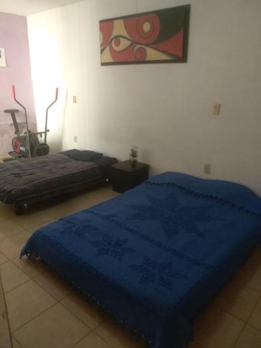 1 dormitorio con 2 camas y manta azul en Casa Valle Dorado SJR Fam, en San Juan del Río