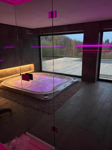 een badkamer met een bad in een kamer met paarse verlichting bij Vila Dvorečná in Loučovice