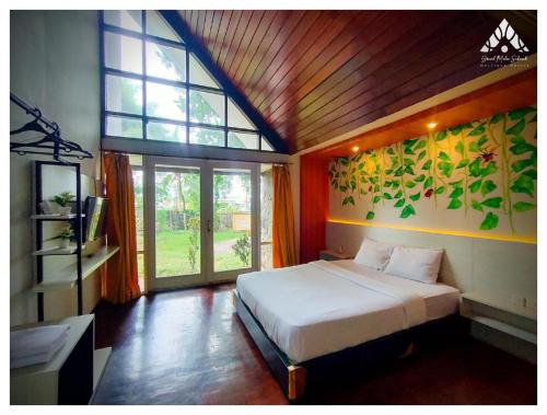 a bedroom with a bed and a large window at Grand Mulia Sakinah Resort & Outbond in Pasuruan
