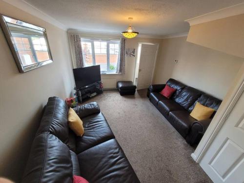 a living room with a leather couch and a tv at Cosy 3 bedroomed home on 3 floors in Darlington