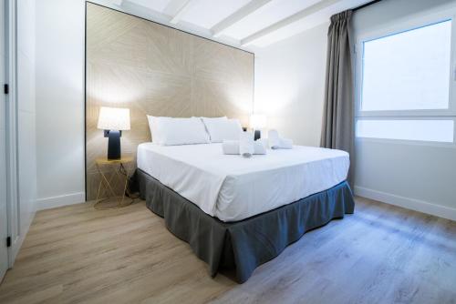 a large white bed in a room with a window at Apartamentos Málaga Premium - Calle San Telmo in Málaga