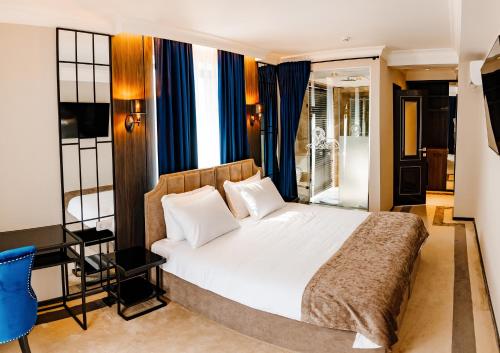 a bedroom with a large bed with blue curtains at Lion's Hotel in Chişinău