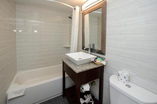 a white bathroom with a sink and a bath tub at Americas Best Value Inn at Central Valley in Central Valley