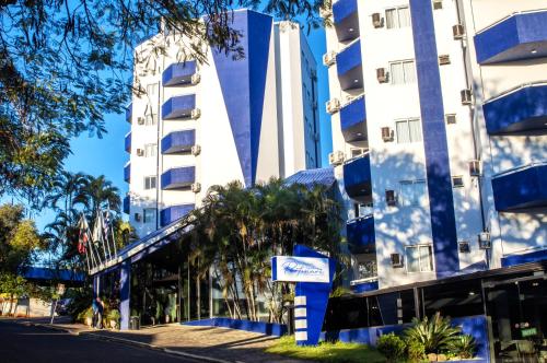 un edificio azul y blanco con palmeras y una calle en Hotel Portinari Centro, en Foz do Iguaçu