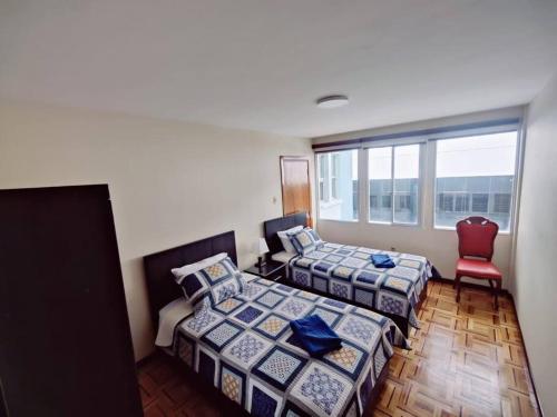 um quarto com 2 camas e uma cadeira vermelha em Cómodo, amplio y céntrico apartamento en Sopocachi em La Paz