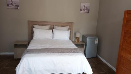 Schlafzimmer mit einem Bett mit weißer Bettwäsche und Kissen in der Unterkunft Bertha's Place in Pretoria