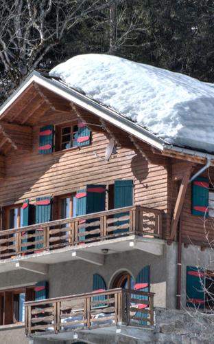 a wooden house with snow on top of it at La Ribambelle in Chamonix-Mont-Blanc