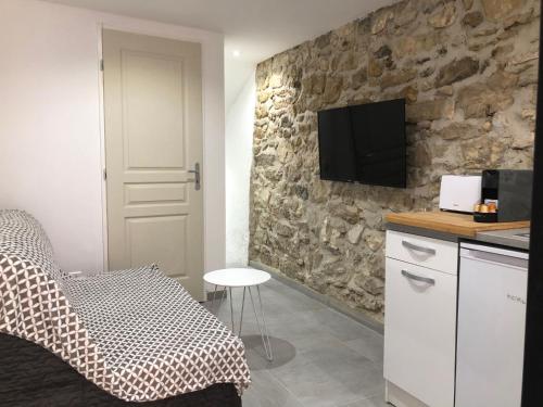 - une chambre avec un lit et une télévision sur un mur en pierre dans l'établissement Les Olives Wifi Netflix Appart-hotel-Provence, à La Fare-les-Oliviers