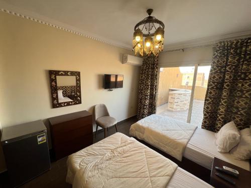 カイロにあるBedouin Pyramids Viewのベッド2台とシャンデリアが備わるホテルルームです。