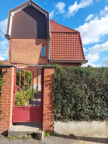 een stenen huis met een rode deur en een heg bij Belle chambre dans un quartier calme in Brussel