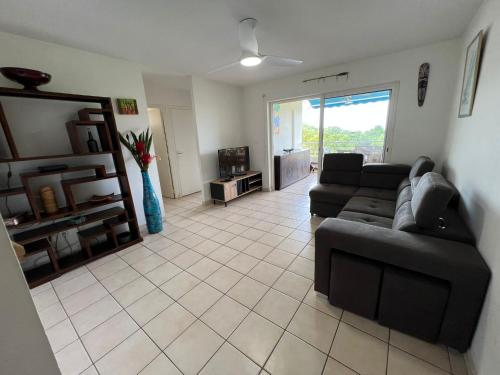 a living room with a couch and a tv at Les Libellules in Les Trois-Îlets