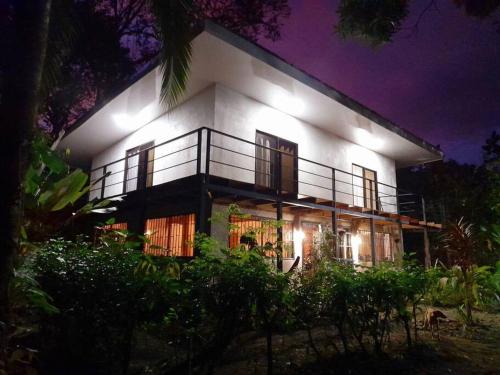 a large white building with people standing outside at night at Miah house in Puerto Jiménez
