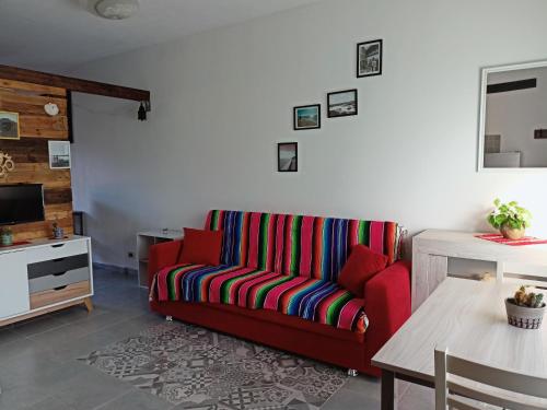 a living room with a red couch and a table at Studio Apartment Residenza del Sole in La Maddalena