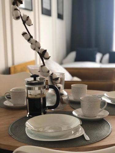 a table with plates and cups and a coffee maker at ApartamentySnu, Struga Tower Gold z parkingiem in Radom