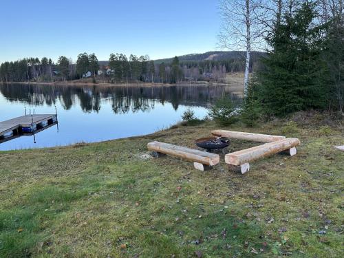 a group of logs on the side of a lake at Villa Granhede -sjöläge med badtunna, eldstad med mera in Torsby