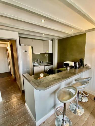une cuisine avec un comptoir et deux tabourets de bar dans l'établissement Superbe T3 duplex parking privé gratuit sur place, à Bordeaux