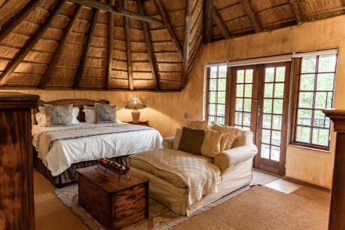 Hotel Nomad Belvedere Lodge في ميدراند: غرفة نوم بسرير وكرسي