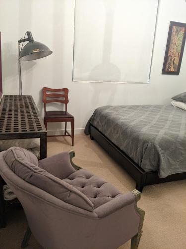 a bedroom with a bed and a chair and a ottoman at Central location close to Downtown and Mountain Views in South Salt Lake