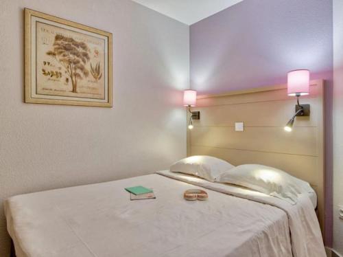 a bed with two pillows and a book on it at Superbe Appartement à 50 m de la mer in Hyères
