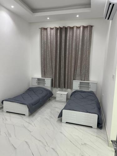 two beds in a bedroom with marble floors at فيلا خاصة في عجمان مكونة من طابقين in Al Ḩamīdīyah