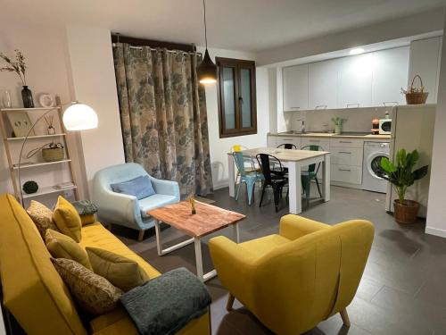 sala de estar y cocina con sofá amarillo y sillas en Coello 31 en Jaén