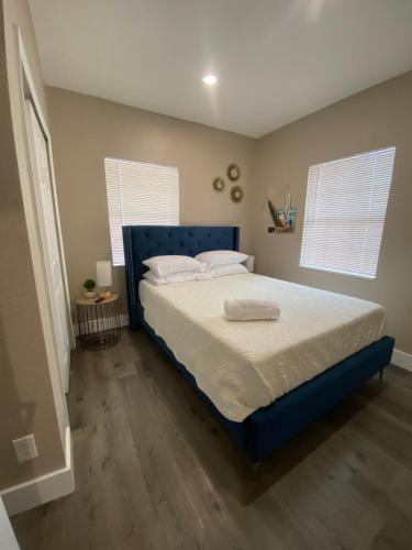 a bedroom with a bed with a blue headboard and two windows at Bella Breeze in Sanford