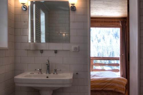 a bathroom with a sink and a mirror and a bed at La Ribambelle in Chamonix