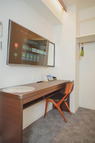 a desk with a television on a wall with a chair at Hotel Plaisir Akihabara in Tokyo