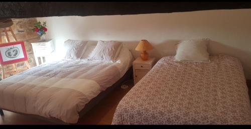 a bedroom with two beds and a lamp on a night stand at chambre familiale 4 pers SDB partagée sans TV in Le Saint