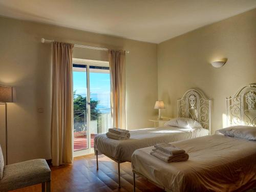 シントラにあるThe Beachfront Casa da Rampa IIのベッドルーム1室(ベッド2台、大きな窓付)